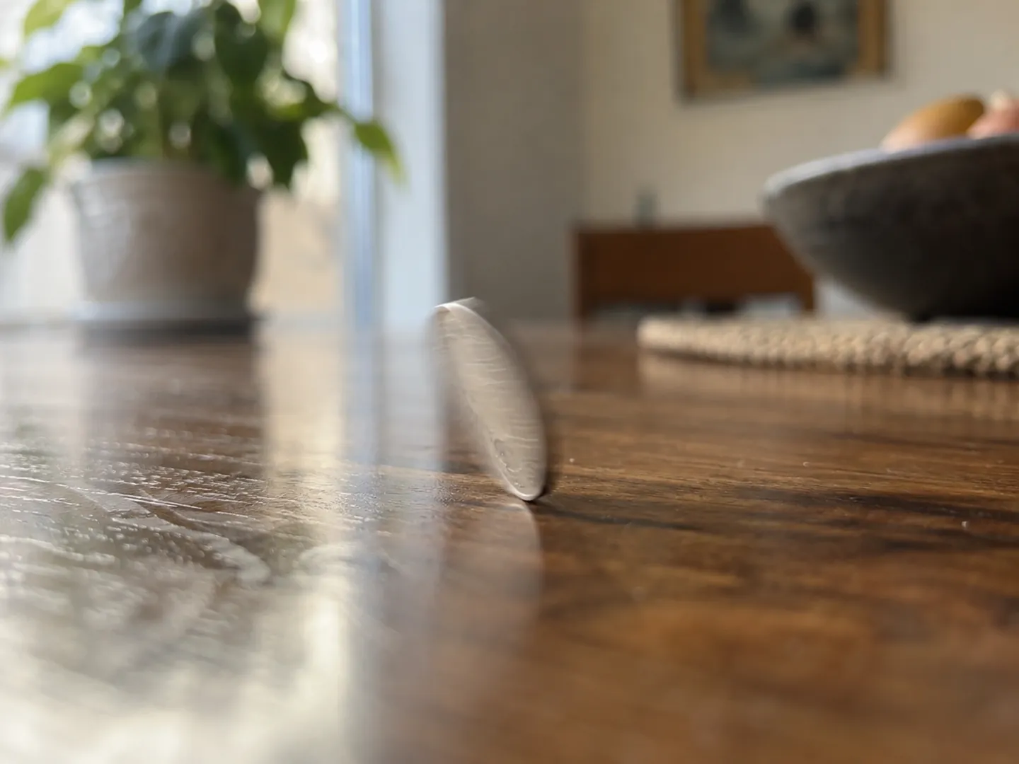 A coin spinning on its edge on a wooden table top, slightly blurred by motion